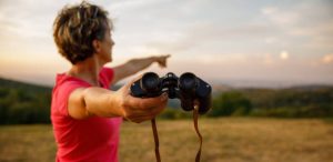 istockphoto-1452691834-612x612 Copy space shot of mature woman giving you binoculars and pointing in the distance, to where to look at while standing on the viewpoint.